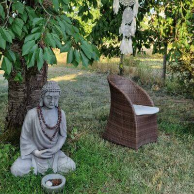 Buddhafigur und Stuhl unter einem Baum