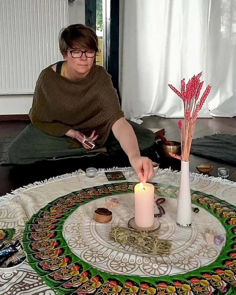 Bild von Sabrina und der Ritualdecke, zündet gerade eine Kerze an